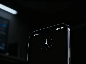 Smartfon z otwartym edytorem zdjęć, na którym palec usuwa cyfrową naklejkę z fotografii.